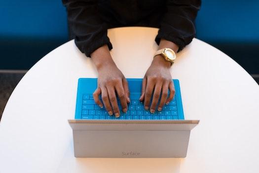 A student's hands type a personal statement on a blue laptop.