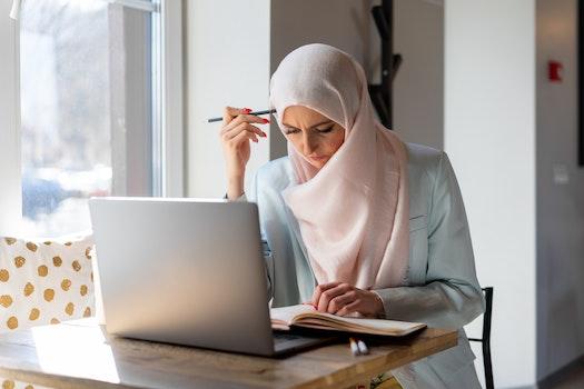 A Muslim woman sits at a laptop studying for her Colorado content area assessments.