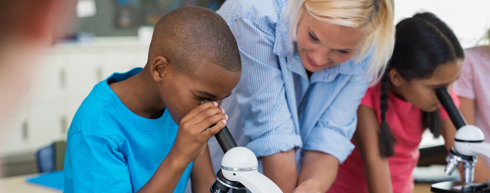 Teacher with student looking through a microscope