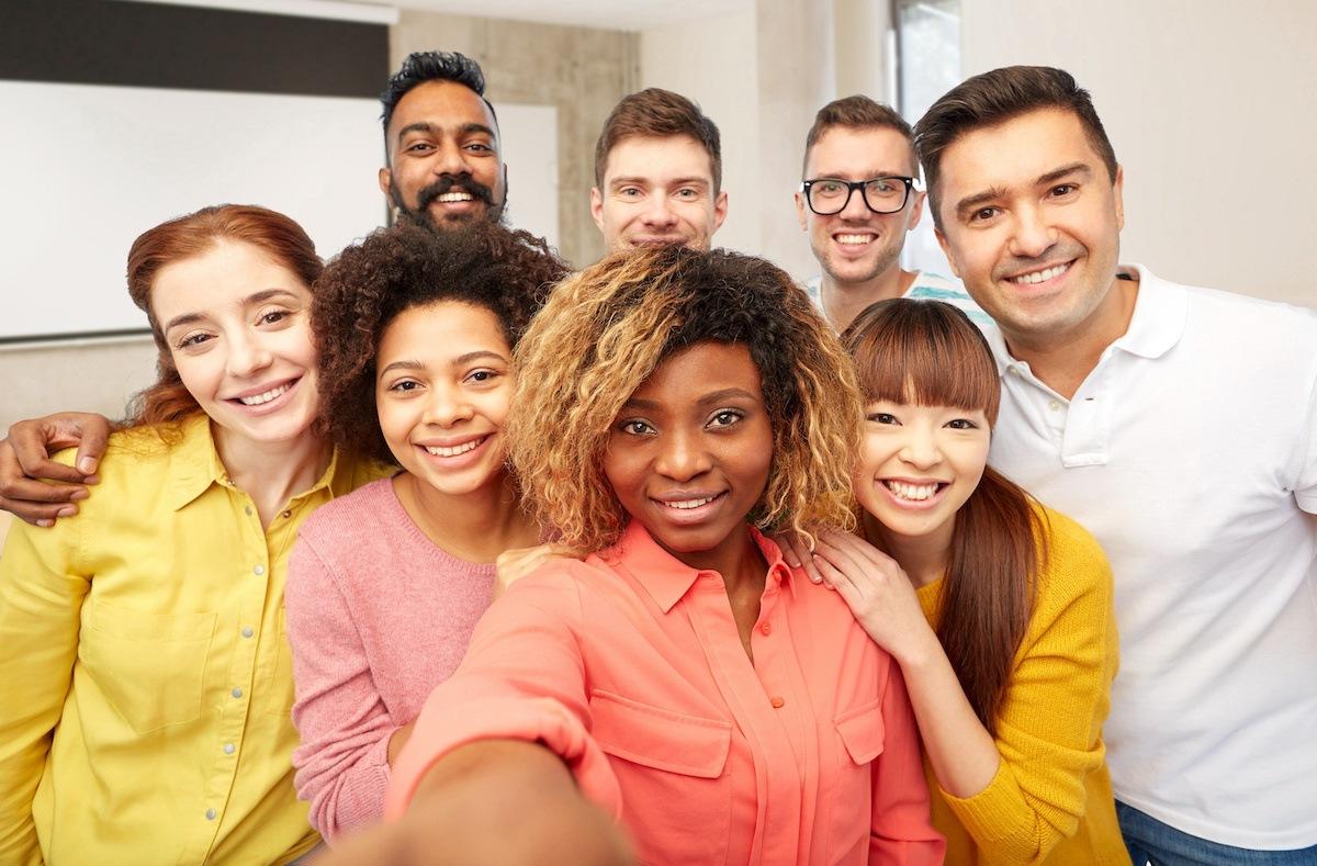 A group of eight diverse future Colorado teachers gather for a group selfie. The person closest to the front holds out the camera in front of her to take the picture.